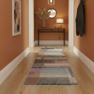 Colorful runner rug on a wooden floor with an orange wall, table, and lamp in the background.