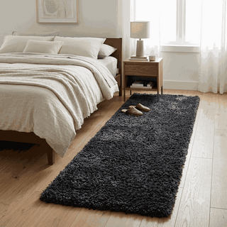A dark charcoal gray shag runner rug styled in a bright, modern bedroom next to a wooden bed and nightstand.