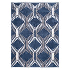 A rectangular area rug with a geometric pattern of interlocking hexagons in shades of navy blue, gray, and white, shown flat against a white background.