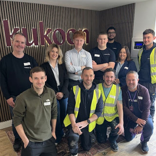 Group of people posing in front of a 'kukoon' sign.