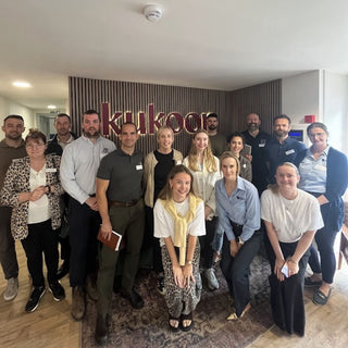 Group of people posing for a photo in an office setting with 'kukoo' branding.
