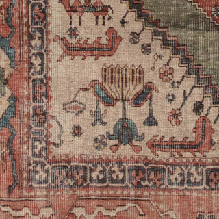 Close-up of an antique Persian-style rug showing detailed woven patterns, a central medallion, and traditional motifs in muted beige, terracotta, and navy blue.