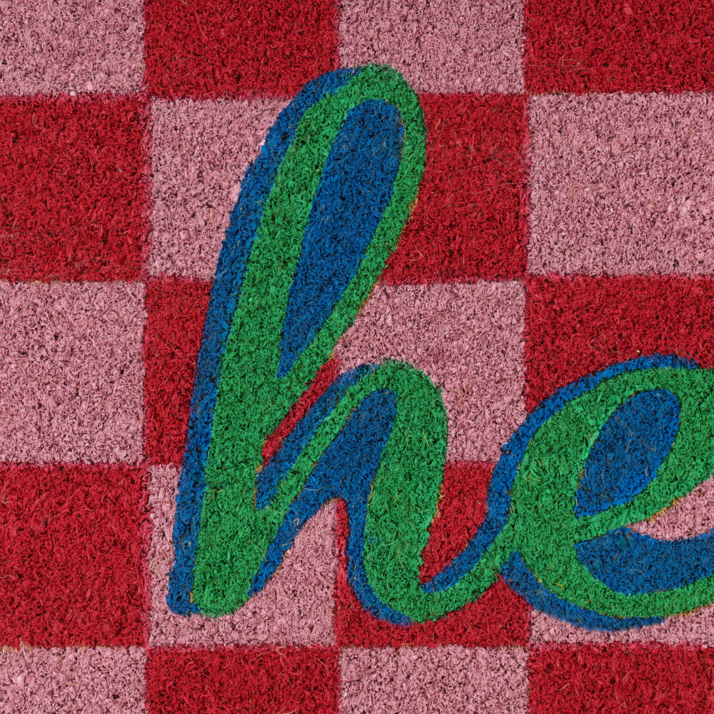 Textured surface with 'hello' in green and blue on a red and pink checkered background