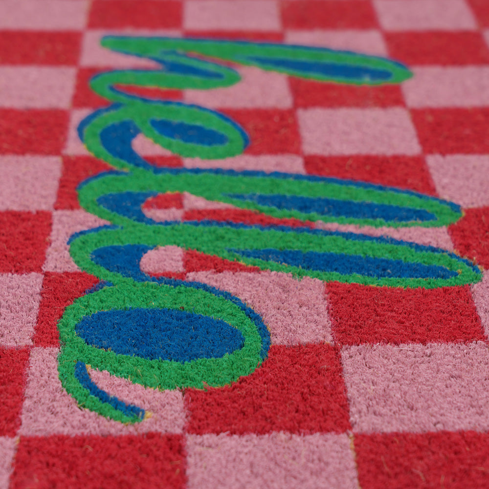 Checkered doormat with 'hello' in green and blue on a red and pink background