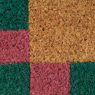 Multicolored doormat with green, pink, and brown squares.
