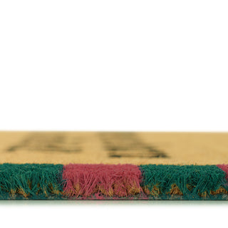 Close-up of a doormat with green and pink fibers on a white background
