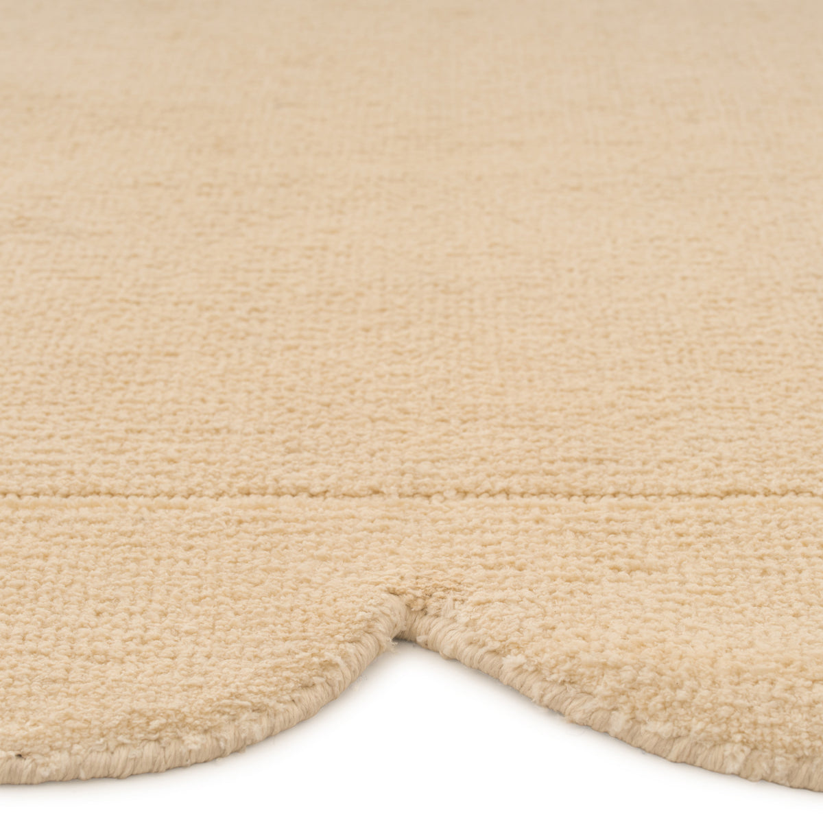 Close-up of a beige textured rug corner on a white background