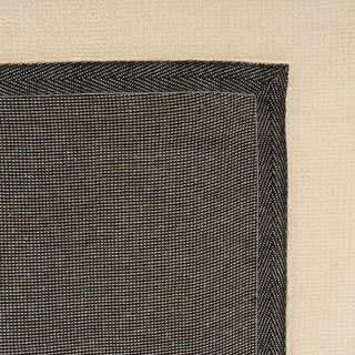 Close-up of a black textured rug corner on a beige background
