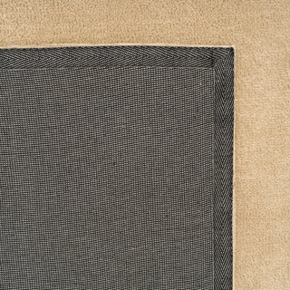 Close-up of a textured black rug corner on a beige carpet