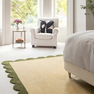 Modern bedroom with a white armchair, bed, and decorative rug.