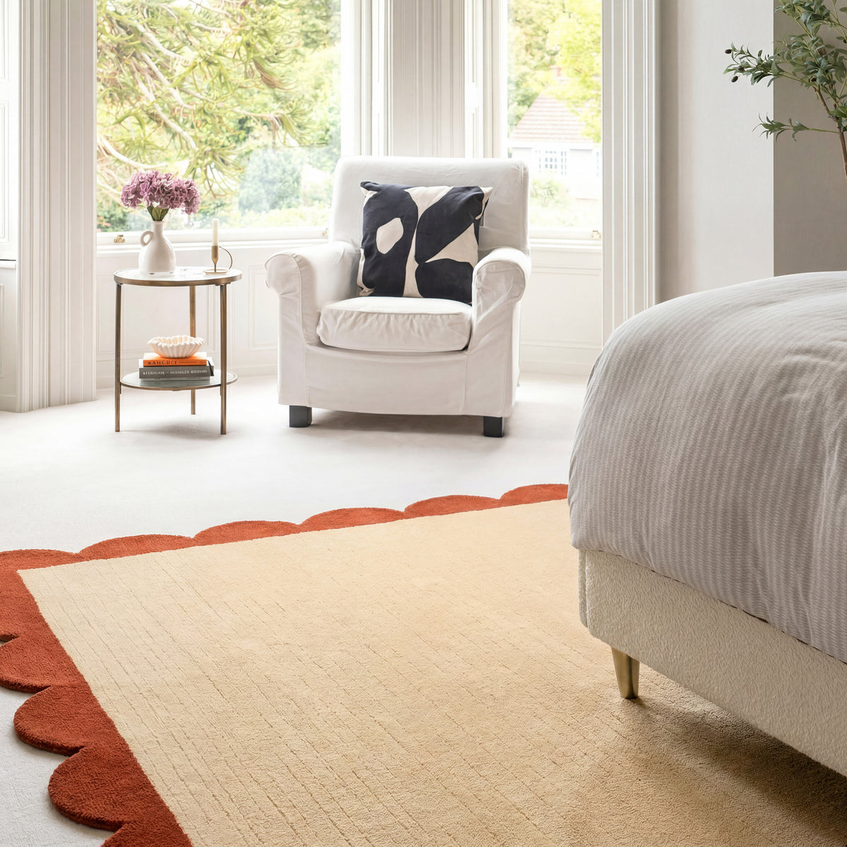 Cozy bedroom with a white armchair, bed, and decorative rug.