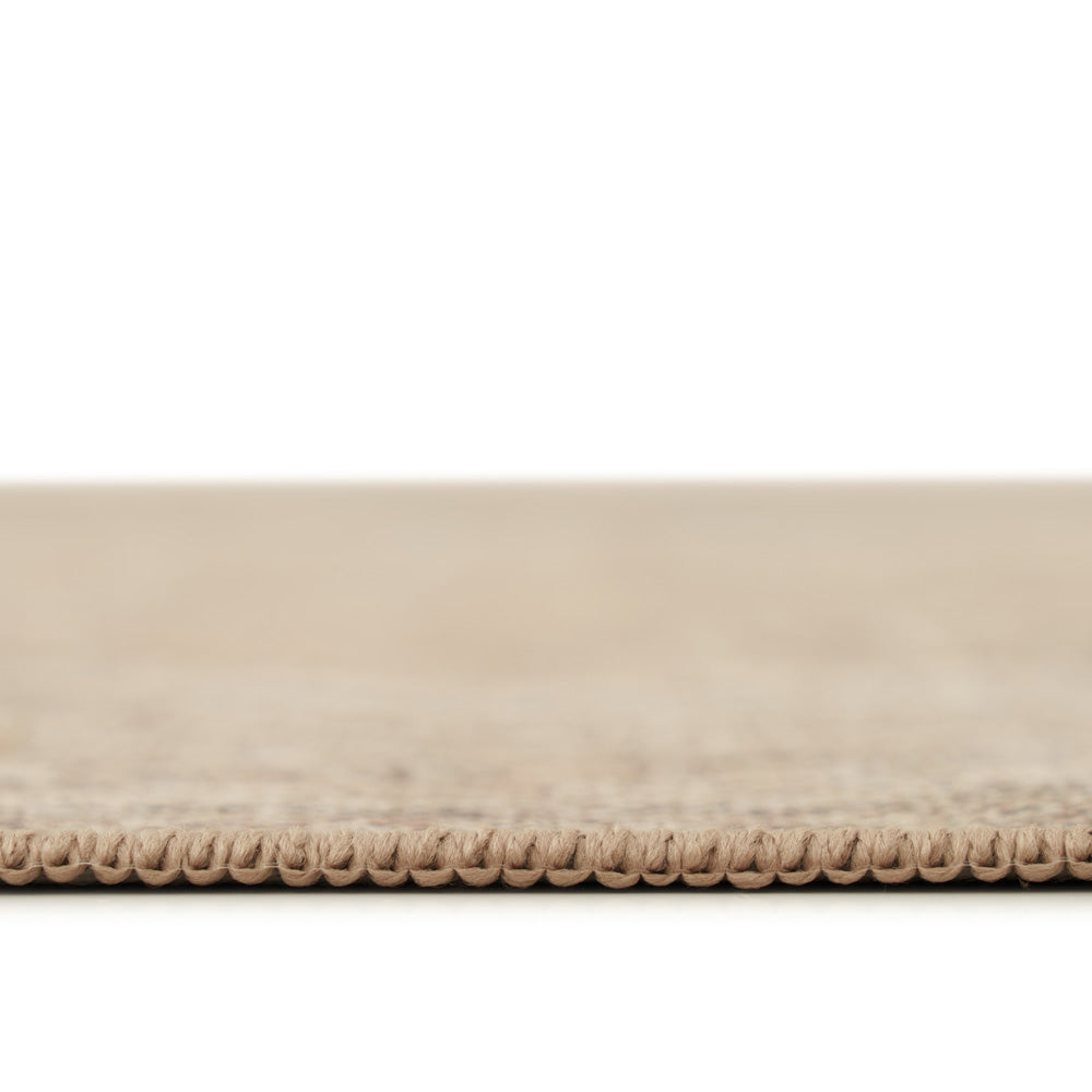 Close-up of a beige woven rug or carpet edge with a textured looped border, shown against a white background.