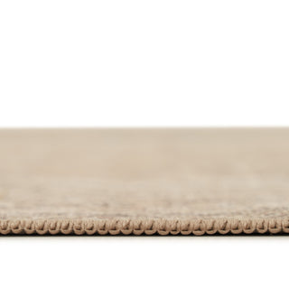 Close-up of a beige woven rug or carpet edge with a textured looped border, shown against a white background.
